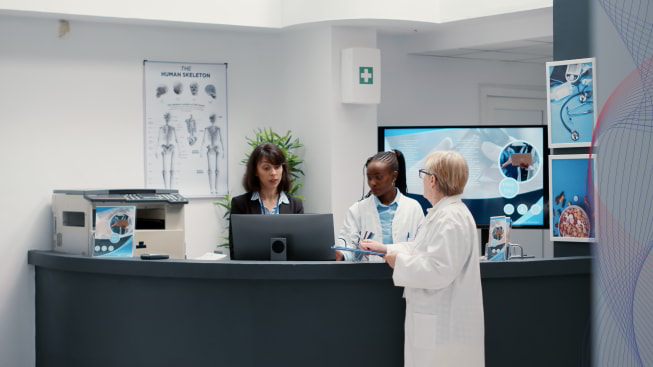 A group of people standing at a hospital reception desk