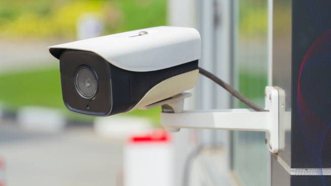 A close-up of a security camera mounted on a building wall outdoors