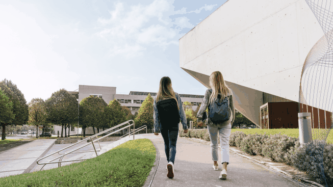 Rear view of two college classmates leaving the university together