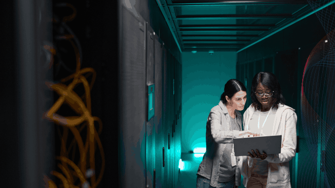 Wide angle portrait of two female IT engineers setting up server network while working in data center