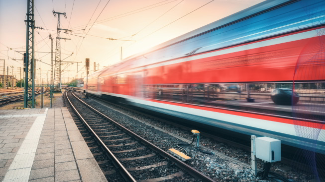 Red high-speed train in motion at the railway station