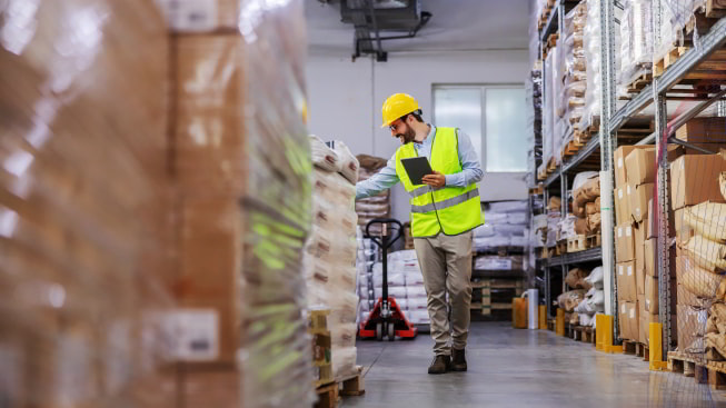 The Supervisor walks around the warehouse and uses a tablet to check on goods for shipment