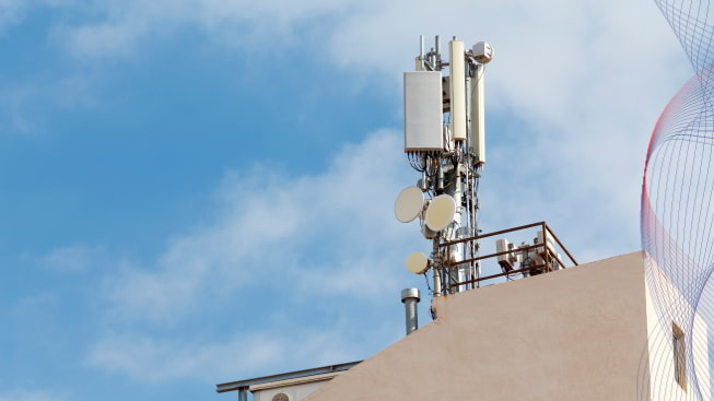 A set of telecommunication antennas on the building roof with the sky at a background