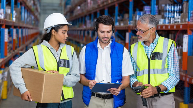 A group of warehouse workers looking at a digital tablet