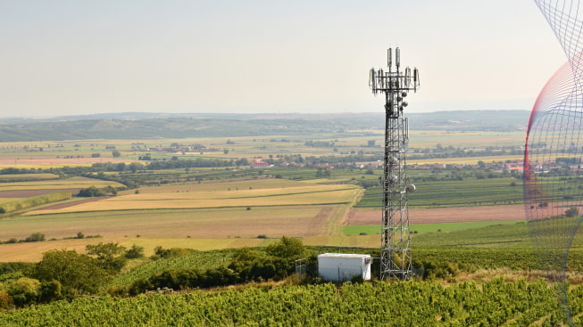 Telecommunication tower mast in a field with villages on a background