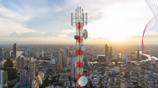 Telecommunication tower with 5g cellular network antenna on city sunset background