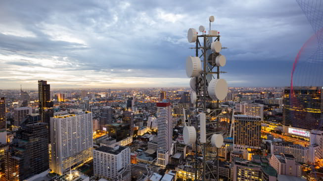 Telecommunication tower with 5g cellular network antenna on night city background