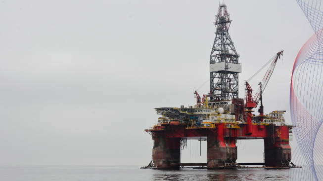 The photo of the platform oil rig placed in the ocean water on the right of the frame