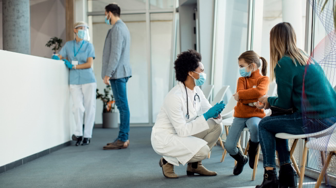 A group of people in a hospital hallway, wearing face masks