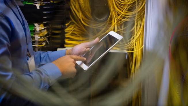 Technician using digital tablet in a server room